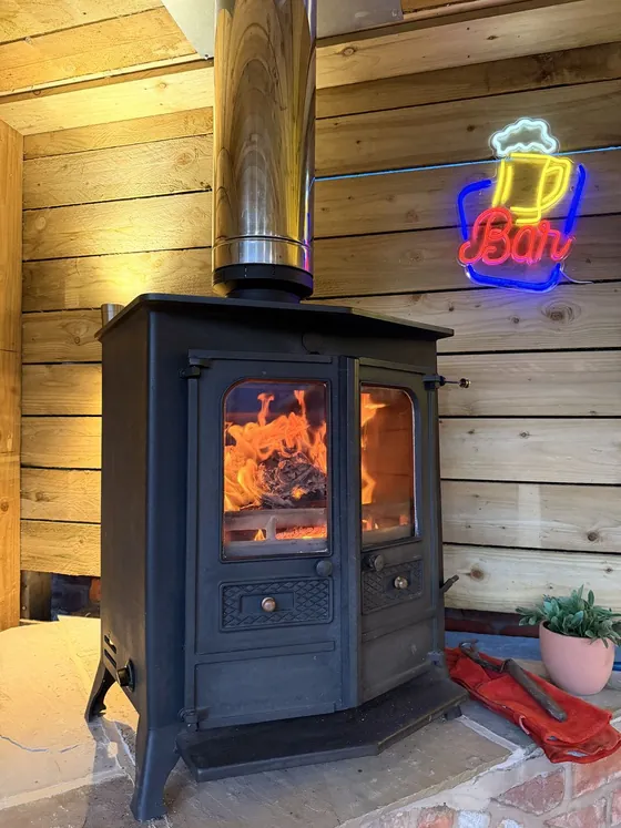 Wood burner installed in a timber-lined room, fire glowing