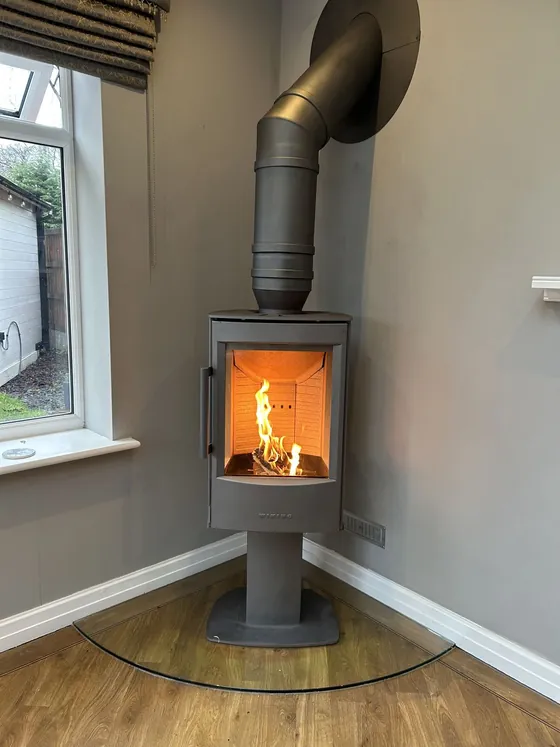 Wood burner with black flue pipe rising to the ceiling
