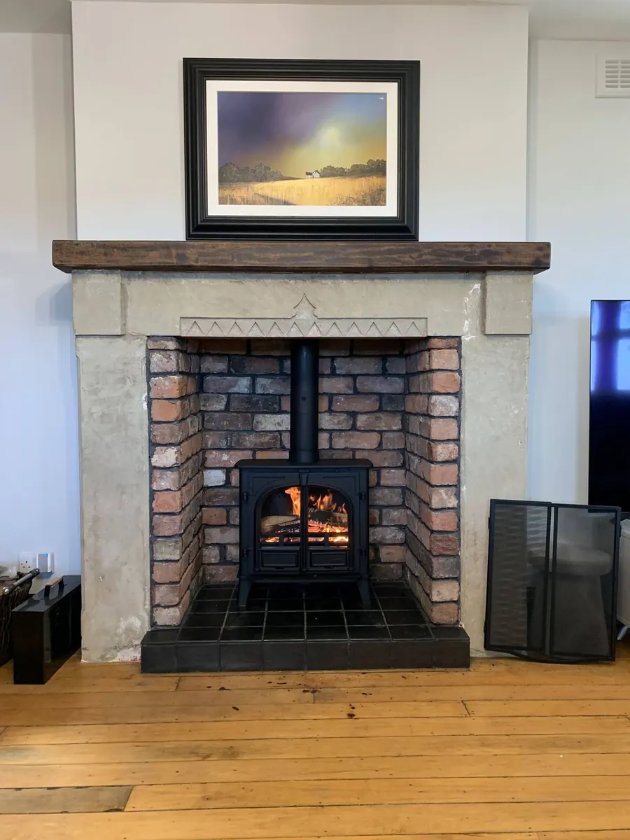 A lit fire in a brick fireplace with a timber lintel in a traditional Lancashire living room