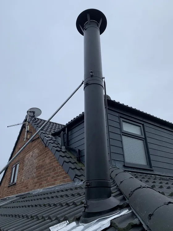 Insulated flue terminating above the roofline with a rain cowl