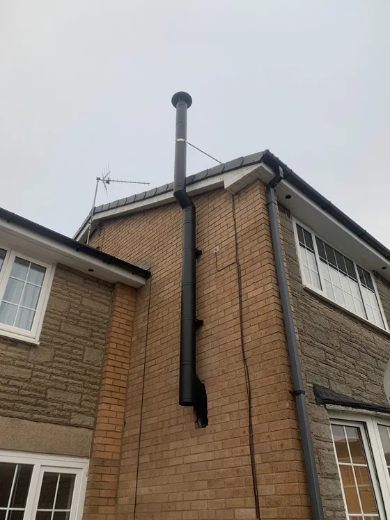 External twin-wall flue run up a brick house wall